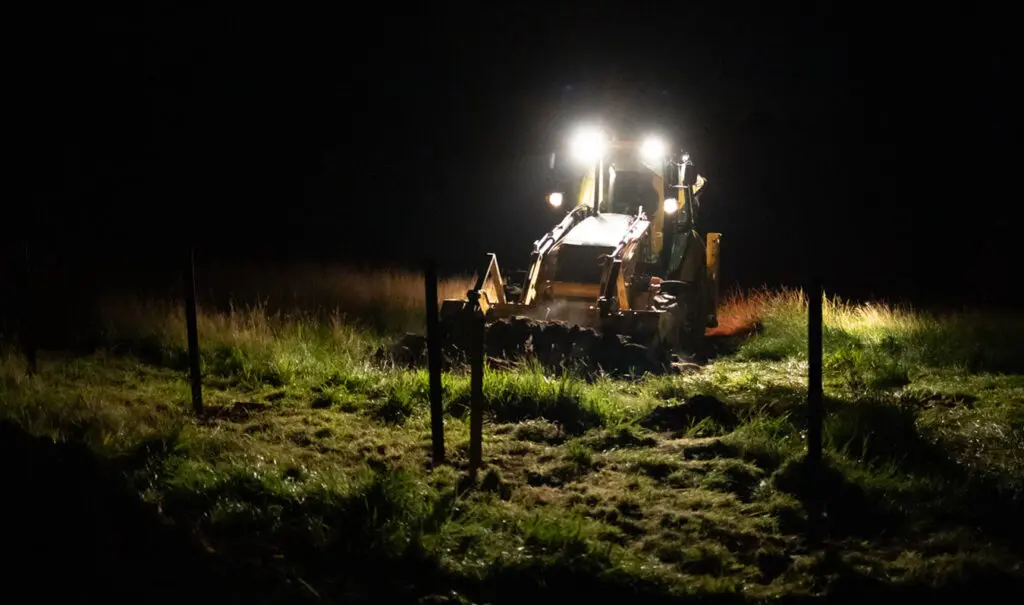 Excavator working at night using vehicle mounted spotlights