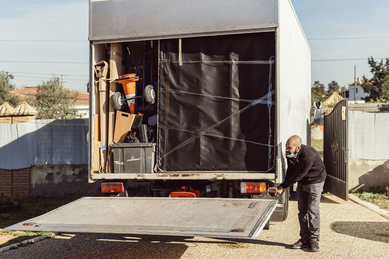 Delivery man lowers tailgate lift to get cargo out of his truck